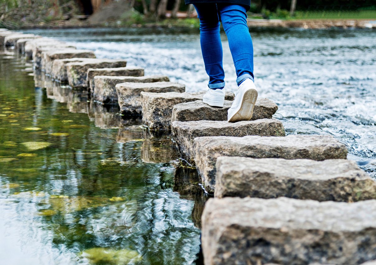 Woman crossing stepping stones on a river